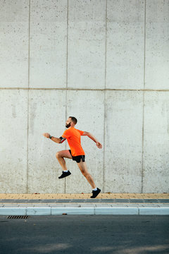 Young bearded man running on the street. Healthy lifestyle concept.