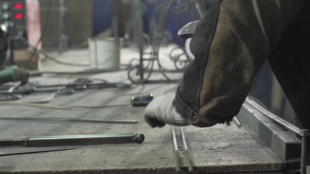 Close-up - A Blacksmith In Protective Gloves Lays Two Iron Rods