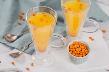 Two high glasses with colorful hot sea buckthorn tea with fresh sea buckthorn berries