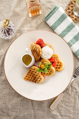 Fresh heart shaped waffles with ice cream and syrup served on the table