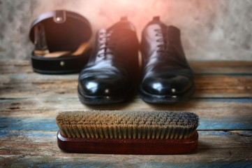 Shoes care concept background with brush for footwear, shoes on a wooden background