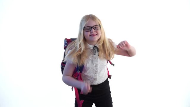 beautiful schoolgirl with a school backpack and wearing glasses dancing in the studio on a white background