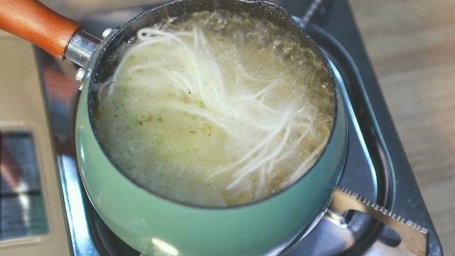 hand holding chopstick stir noodle in pot , Asian cooking cuisine food concept