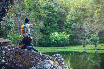 Couple sitting on rocks and taking pictures nature, flowers. at Paphiopedilum orchid conservation center.