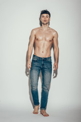 sexy shirtless macho in jeans posing on grey