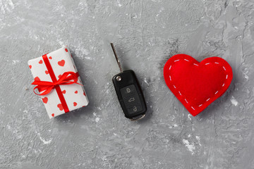 Valentine or other holiday handmade present in paper with red hearts, car keys and gifts box in holiday wrapper. box gift on gray cement table top view with copy space, empty space for design