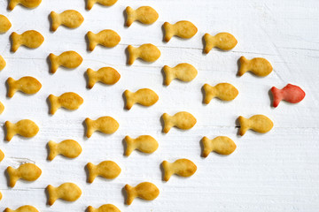 Leadership or follow the leader concept with small cookies with fish shape on white wooden background