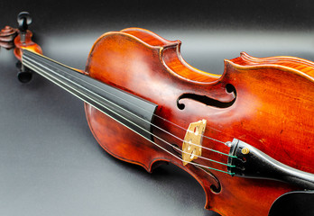 Professional violin in a dynamic position slightly tilted to the side, shot in a studio on a dark background with similar to concert light lighting