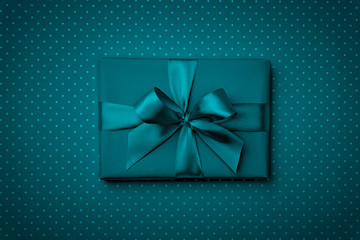 Gift box  with bow and ribbon top view on dark blue or turquoise background. Flat lay. Top View