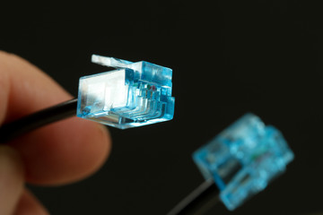 Man holding cable with blue rj-45 connector on black