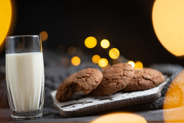 Photo glass of milk with homemade cookies, beautiful background with lights in blur