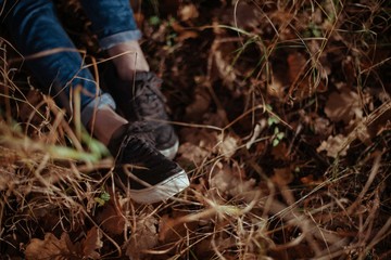 Women's legs in jeans and sneakers in the dry grass