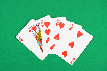 top view of green poker table and unfolded playing cards with hearts suit