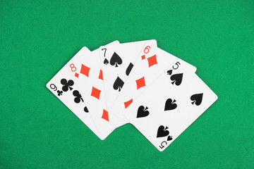 top view of green poker table and unfolded playing cards with different suits
