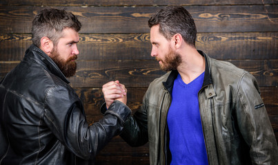 Have agreed. Brutal bearded men wear leather jackets shaking hands. Strong handshake. Friendship of...