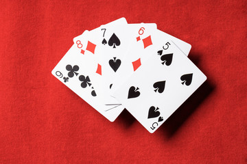 top view of red table and unfolded playing cards with different suits