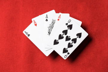 top view of red poker table with unfolded playing cards, four aces and nine