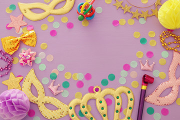 carnival party celebration concept with mask and colorful party accessories over purple wooden background. Top view. Flat lay.