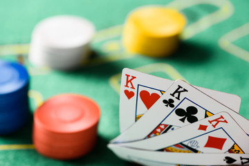 selective focus of playing cards with chips and green poker table on background