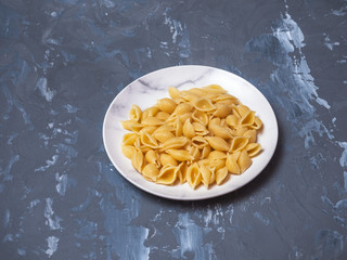 Close-up of pasta in the form of shells on a white plate.