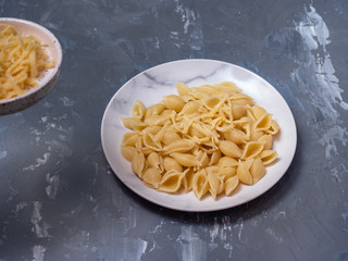 Close-up of pasta on a white plate, in the background a saucer with grated cheese.