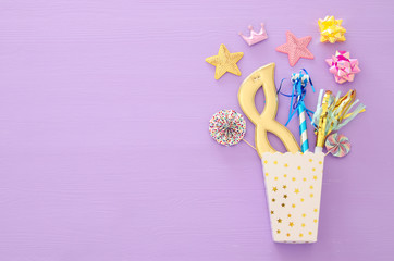 carnival party celebration concept with mask and colorful party accessories over purple wooden background. Top view. Flat lay.