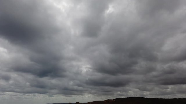 Tilting down from cloudy sky revealing 12 Apostle rocks at Great Ocean Road, VIC, Australia