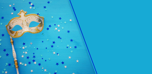 carnival party celebration concept with elegant gold mask on stick over blue wooden background and...