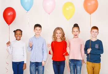 Group of children with colourful balloons over wall