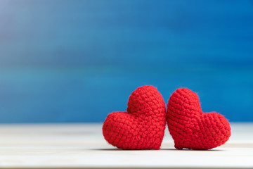 Valentines day concept. hand make two yarn red heart on wooden table and blue background