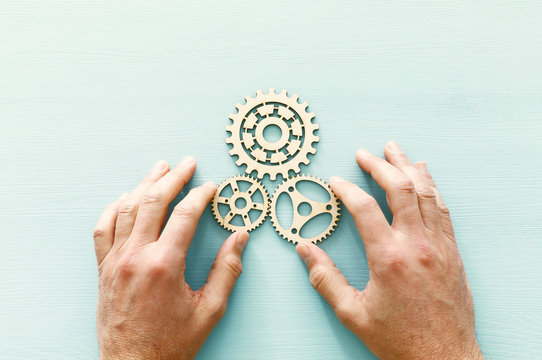 hand placing a cogwheel in set of gears mechanism