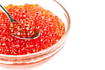 Red caviar in glass jar with spoon on white background. Sea food. Healthy eating. Diet. Selective focus.