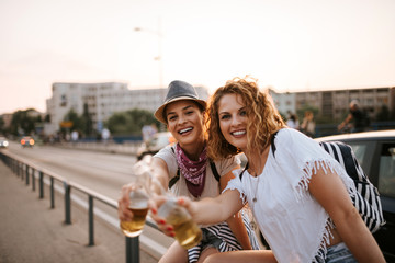 Two young female friends enjoying drinks in the summer.