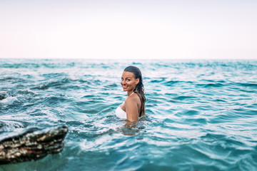 Gorgeous woman standing in the sea water. Looking at camera. Genuine emotions.