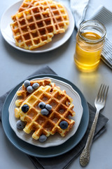 Belgian waffles with blueberries and honey on gray wooden background. Homemade healthy breakfast. Selective focus