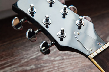 Guitar head with tuning pegs without strings and neck with fingerboard, frets and nut.