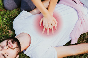 Hands are pressing to the chest. First Aid by Basic Heart Pump, a man wearing a white shirt shows a sick person who gets an accident. And this may be caused by Heat Stroke. First aid is needed.