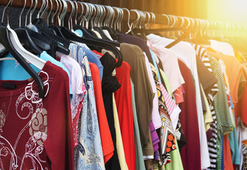 clothes rack with vintage second hand women's fashion. filtered image with sun flare.