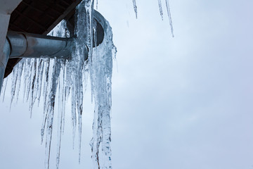 Ice on the roof and downpipe on a winter day.