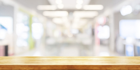 Empty wooden table top with blurred modern shopping mall background. Panoramic banner.