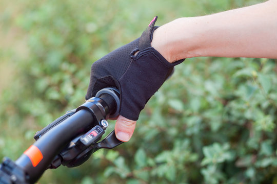 Fototapeta A girl in bicycle gloves holds her hand on the handlebars, clamping the brakes.