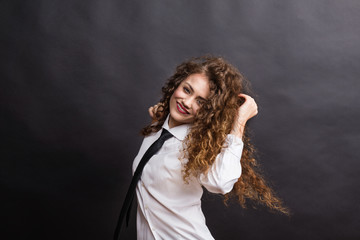 Young beautiful happy woman in studio, wearing white shirt and black tie.