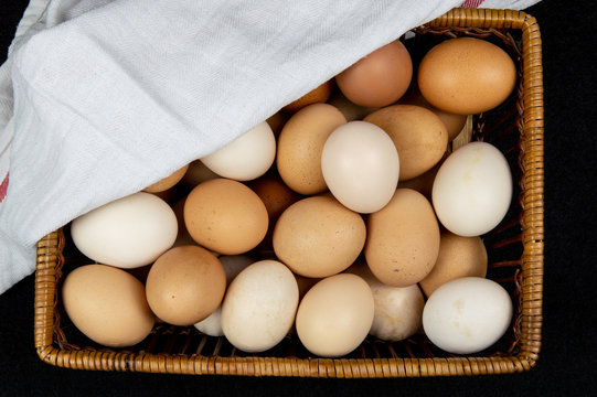 Top view of chicken eggs in a basket on a black background