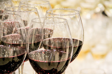 Catering services. Red wine in in glasses in several rows at restaurant party. Shallow depth of field.