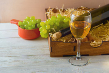 wine bottle, glass, grapes in wooden box,