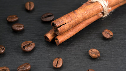 cinnamon and grains of coffee on a black background