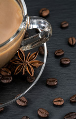 Coffee cup with beans, anise and cinnamon sticks on dark background