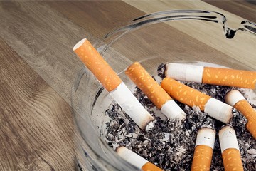 Ashtray and smoked cigarettes on wooden background