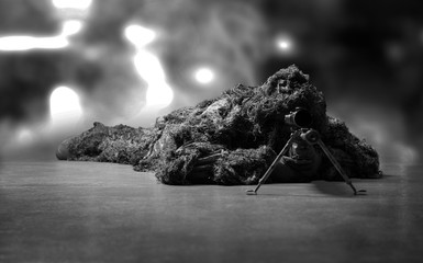 The sniper in disguise lies with a sniper rifle and aims at the telescopic sight.