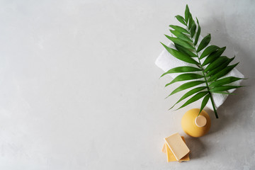 Spa concept: beautiful ceramic bottle, handmade organic soap, white towels and palm leaf on concrete light surface with copy space, flat lay. - obrazy, fototapety, plakaty